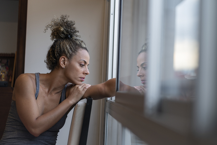 A woman looks out the window as she struggles with substance use problems.