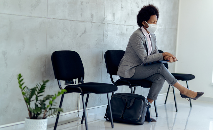 A woman sits pensively in the hallway waiting for a job interview