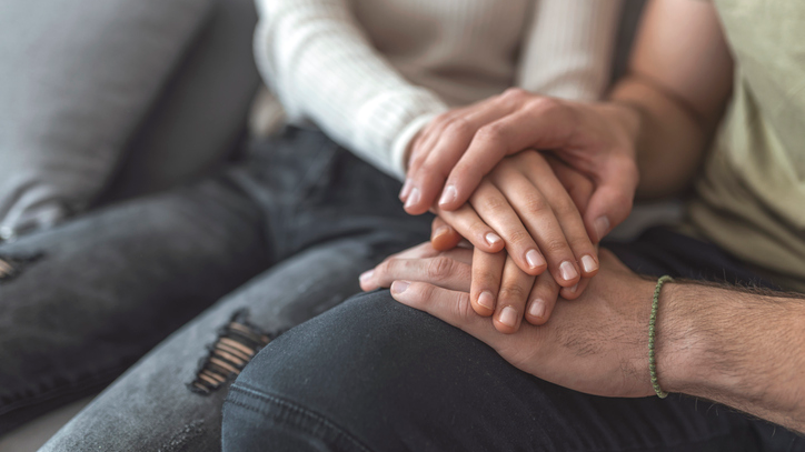 Close up of young people hand in hand sitting (2)