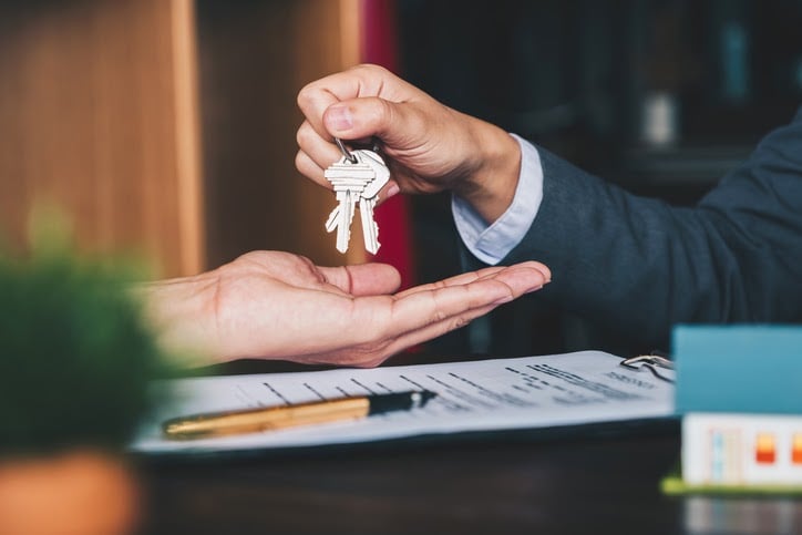 Man handing keys to new home owner first time home buying