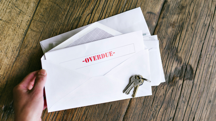 Overdue Notiice in an Open Envelope with Keys on a Wood Table - Hands of a Woman Holding - Late Bills - Rent - Mortgage - stock photo