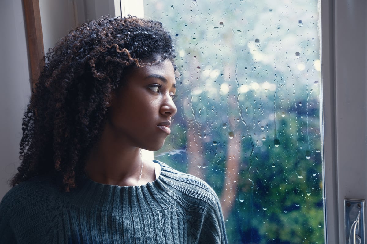 Woman looks out of the window in rain.