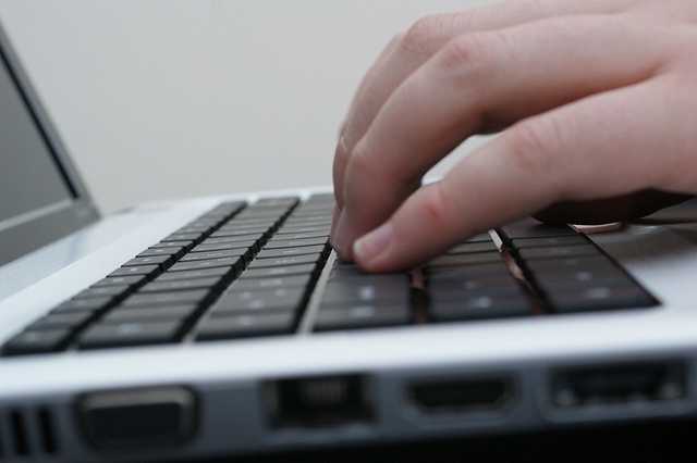 Hands typing on a laptop computer