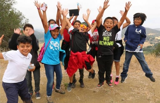 A group of students pose on top of a mountain at a national park.