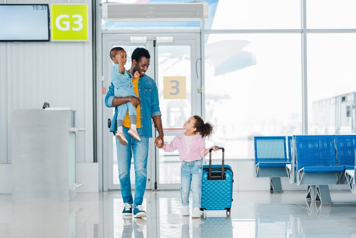 smiling father walking with children along waiting hall in airport