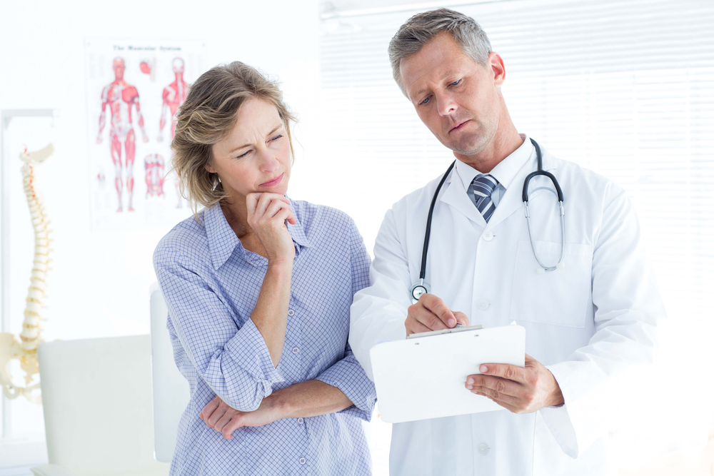 Doctor showing his notes to his patient in medical office